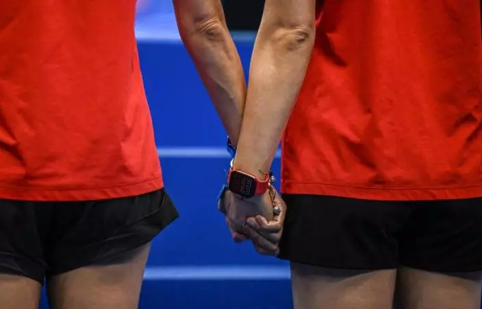 7月18日，福岡世錦賽，集體技術自選比賽前，中國隊教練賀曉初（右）、張曉歡在中國隊入場時兩手緊握。新華網圖片