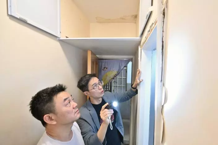 專業支援: 關愛隊聯絡測量師(右)上門為湯先生的單位免費檢查,提供處理滲水問題的建議。政府新聞網圖片