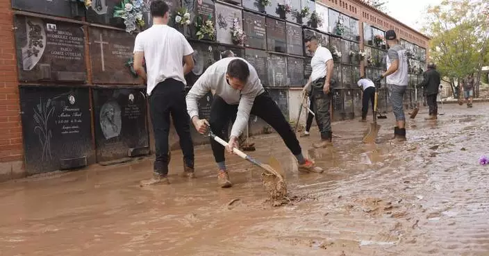 Mud-caked volunteers clean flood debris in a Spanish town as authorities struggle to respond