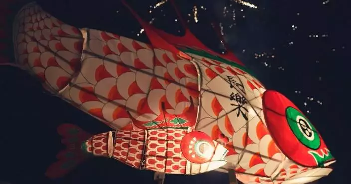 Traditional fish lanterns illuminate night sky of ancient Chinese town