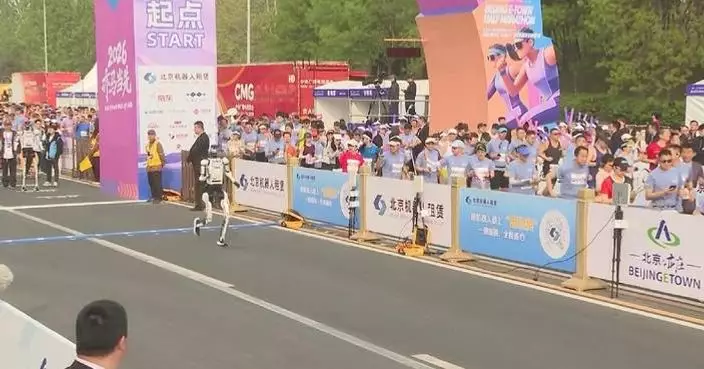 Half-marathon runners impressed by fast progress of robots running aside