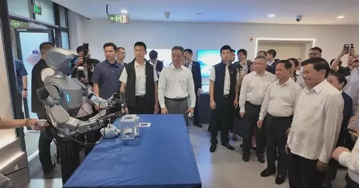 Lao top leader Thongloun interacts with robots during China visit